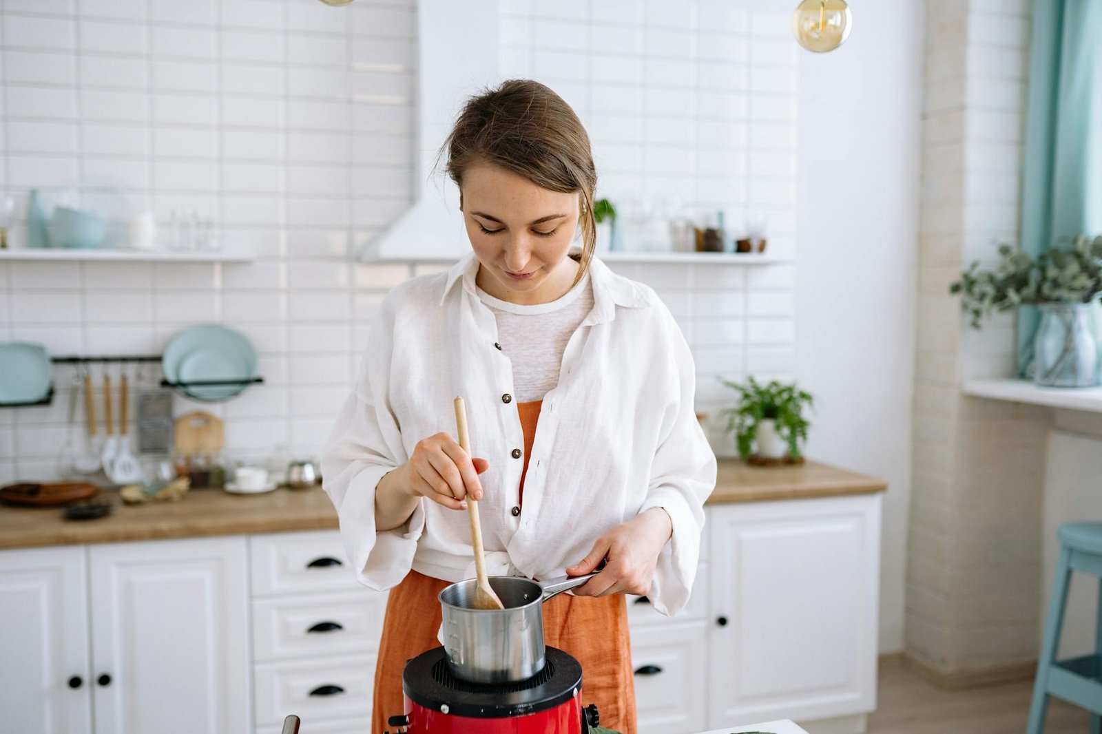 Ceramic or Stainless Steel Cookware: Which is Easier to Clean and Maintain 2 Young woman stirring pot in bright kitchen setting with wooden spoon.