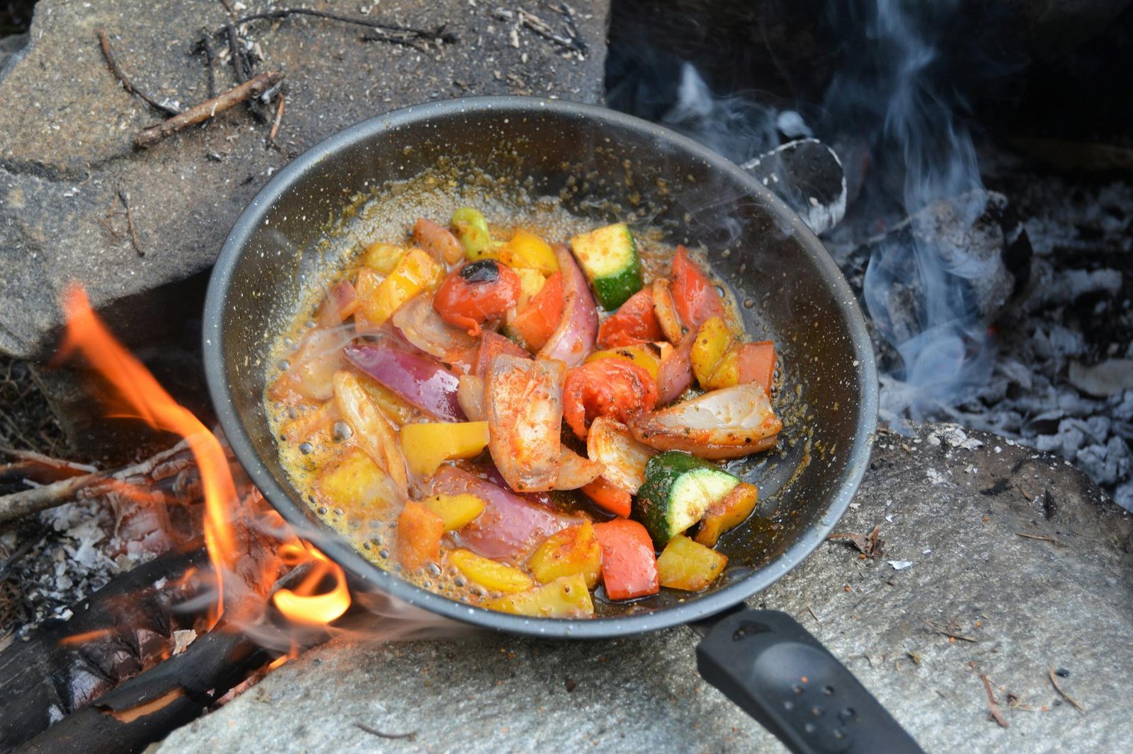 Ceramic or Stainless Steel Cookware: Which is Easier to Clean and Maintain 3 A vibrant assortment of vegetables sizzling in a skillet over a campfire, perfect for outdoor cooking inspiration.