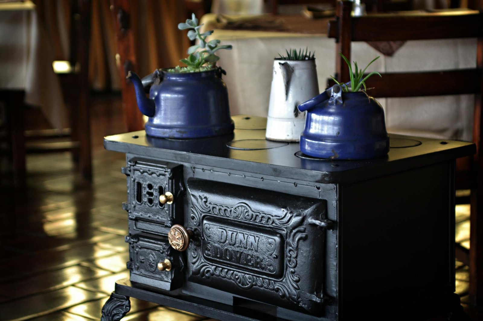 A vintage stove with blue kettles and plants, creating a rustic indoor atmosphere.