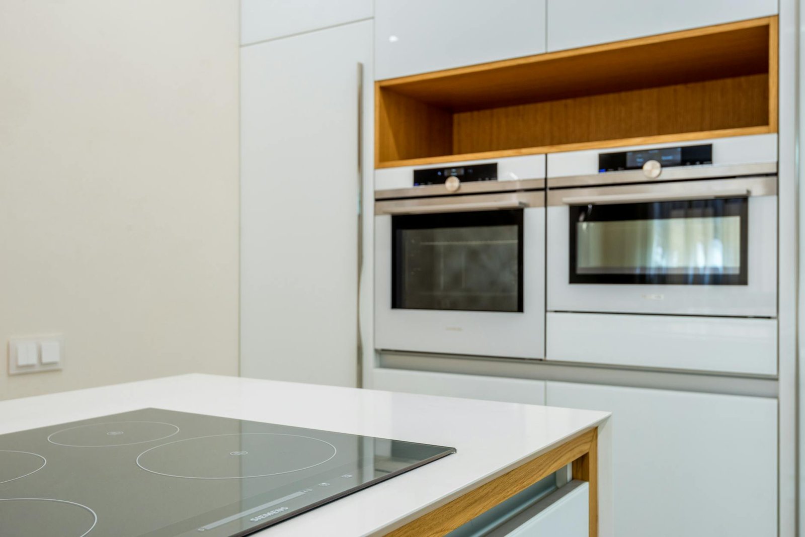Interior of contemporary light kitchen with white ovens and clean new stove in modern apartment