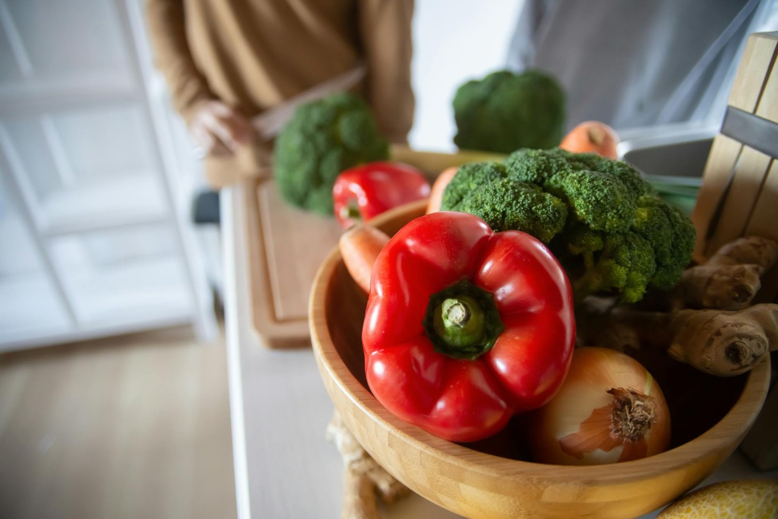 Debunking the High Heat Myth for Perfect Sear on Gas Stoves 3 A close-up of fresh vegetables including red peppers, broccoli, and ginger in a wooden bowl.