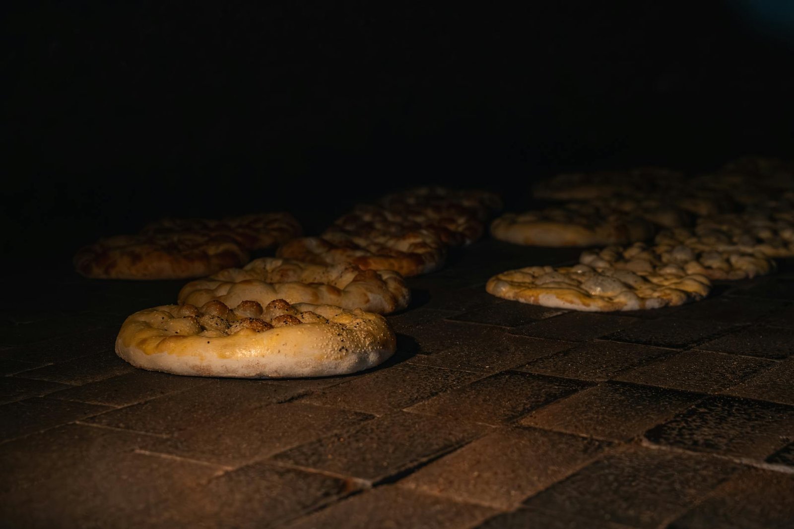 Traditional flatbreads baking in a dimly lit brick oven, showcasing artisanal bread making.