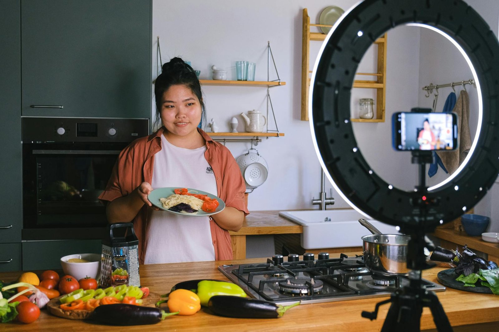 Descale Your Stove's Electric Heating Elements for Better Cooking Performance 2 A woman demonstrates cooking in a stylish kitchen while filming content. Perfect for culinary and lifestyle themes.