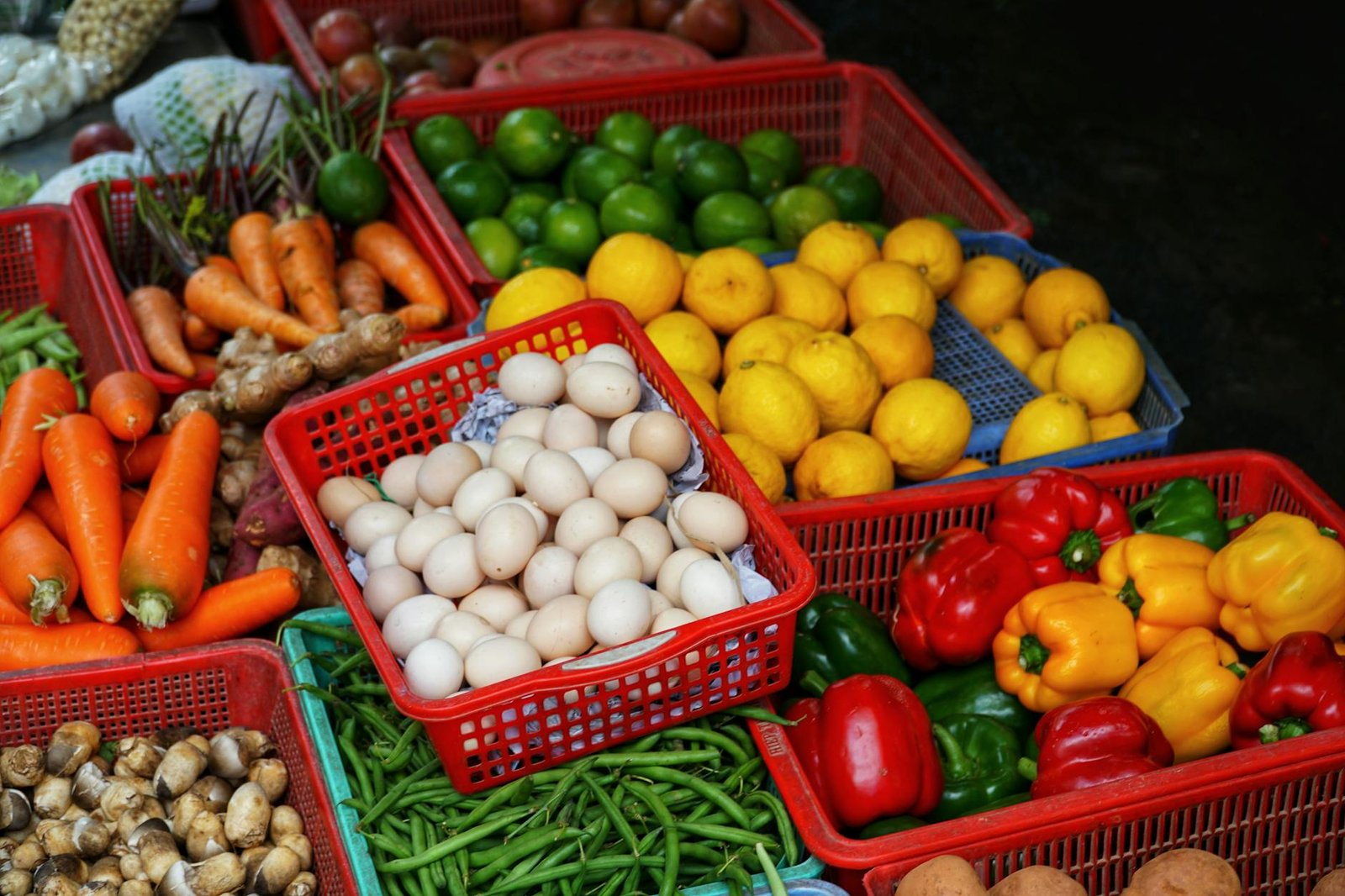 From above of collection of colorful ripe vegetables and citrus fruits in plastic boxes in street market