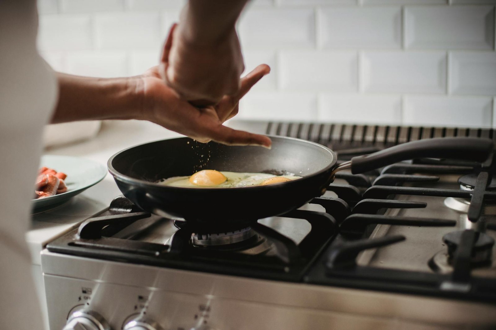 Electric Stoves with Coil Burners vs Ceramic Burners: Safety and Energy Comparison 1 Close-up of frying eggs on a gas stove with hands seasoning the dish.