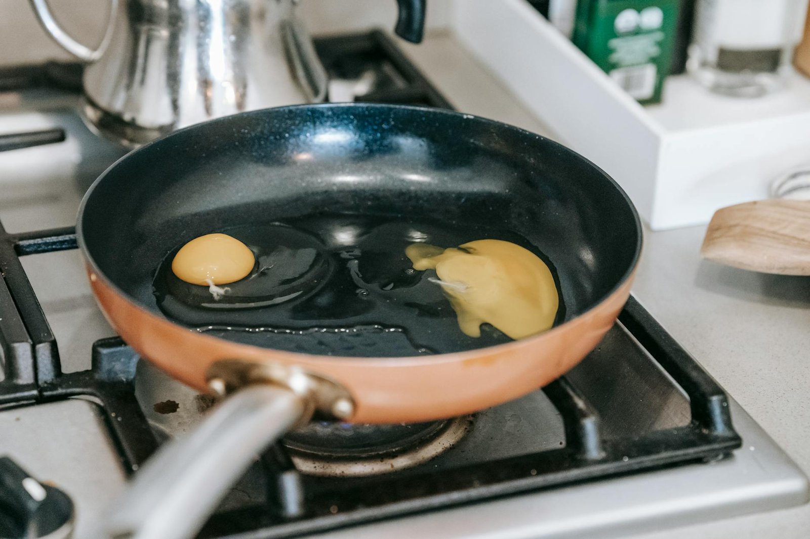 Two eggs frying in a non-stick pan on a stovetop, perfect for breakfast.