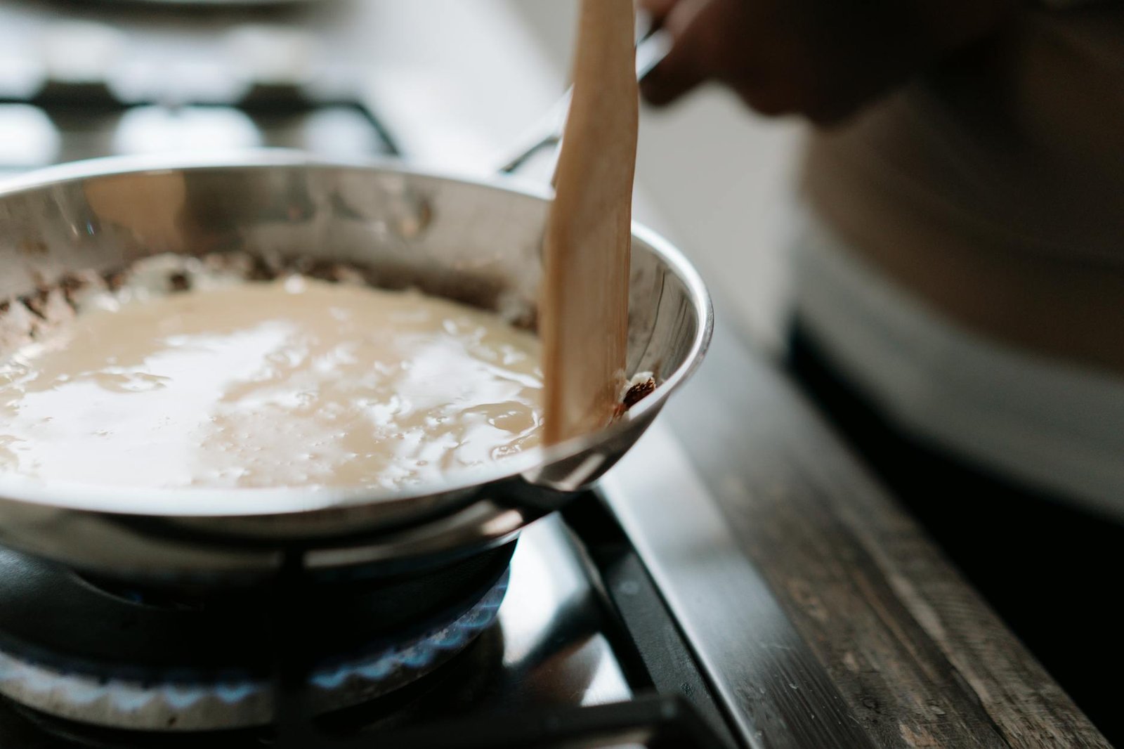 A close-up of sauce being stirred in a pan on a stove, highlighting cooking techniques.