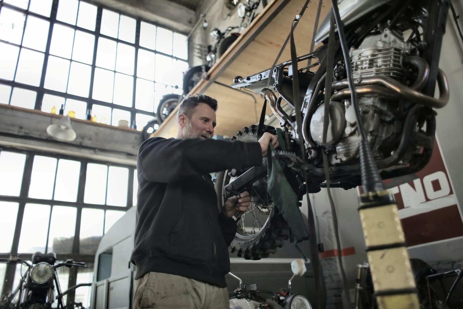 Mechanic fixing a motorcycle in a garage workshop, focused on maintenance.