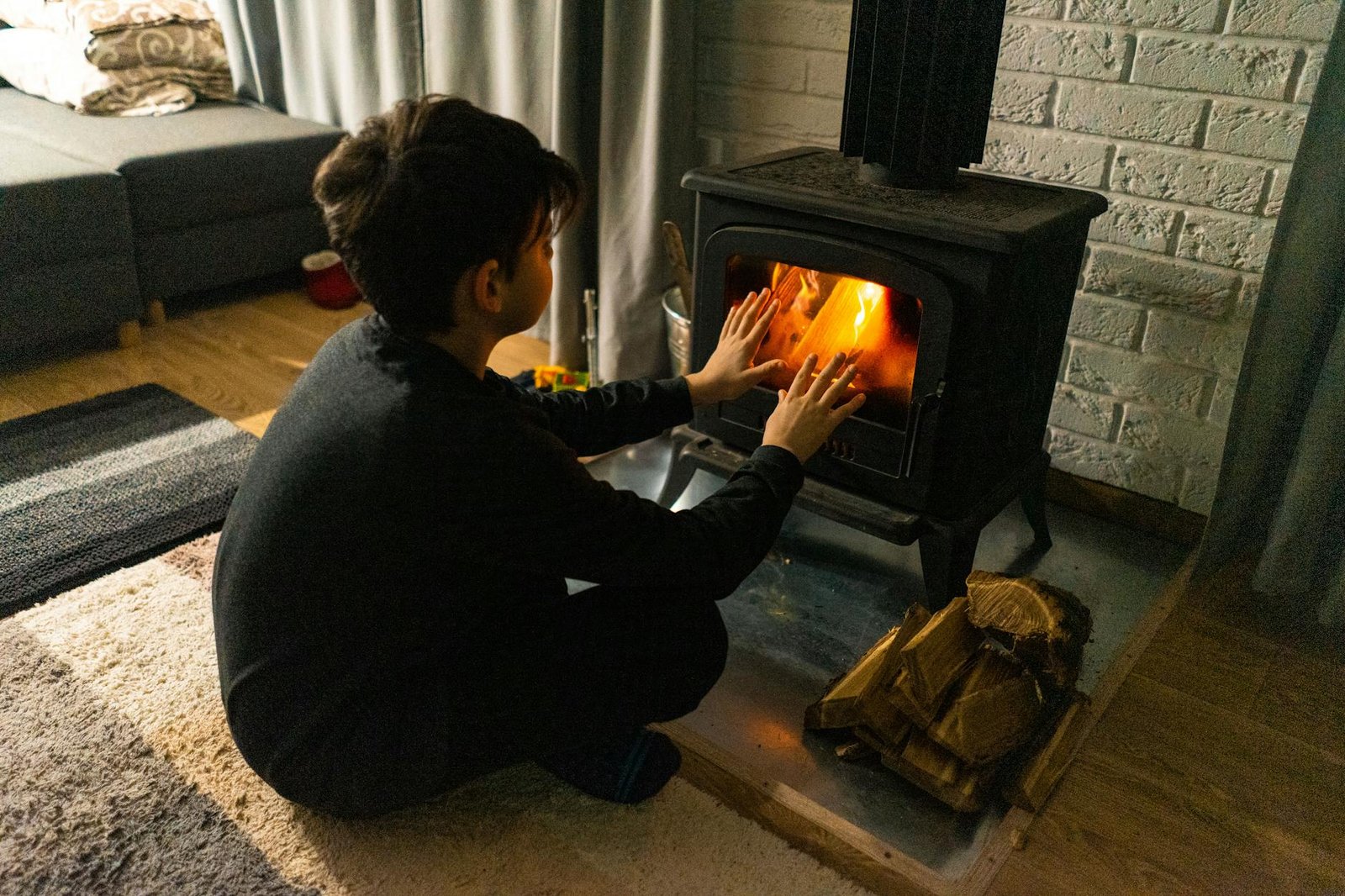 Fixing Common Stove Issues for Beginners 3 A child warms hands by a wood stove in a cozy living room, creating a warm winter ambiance.