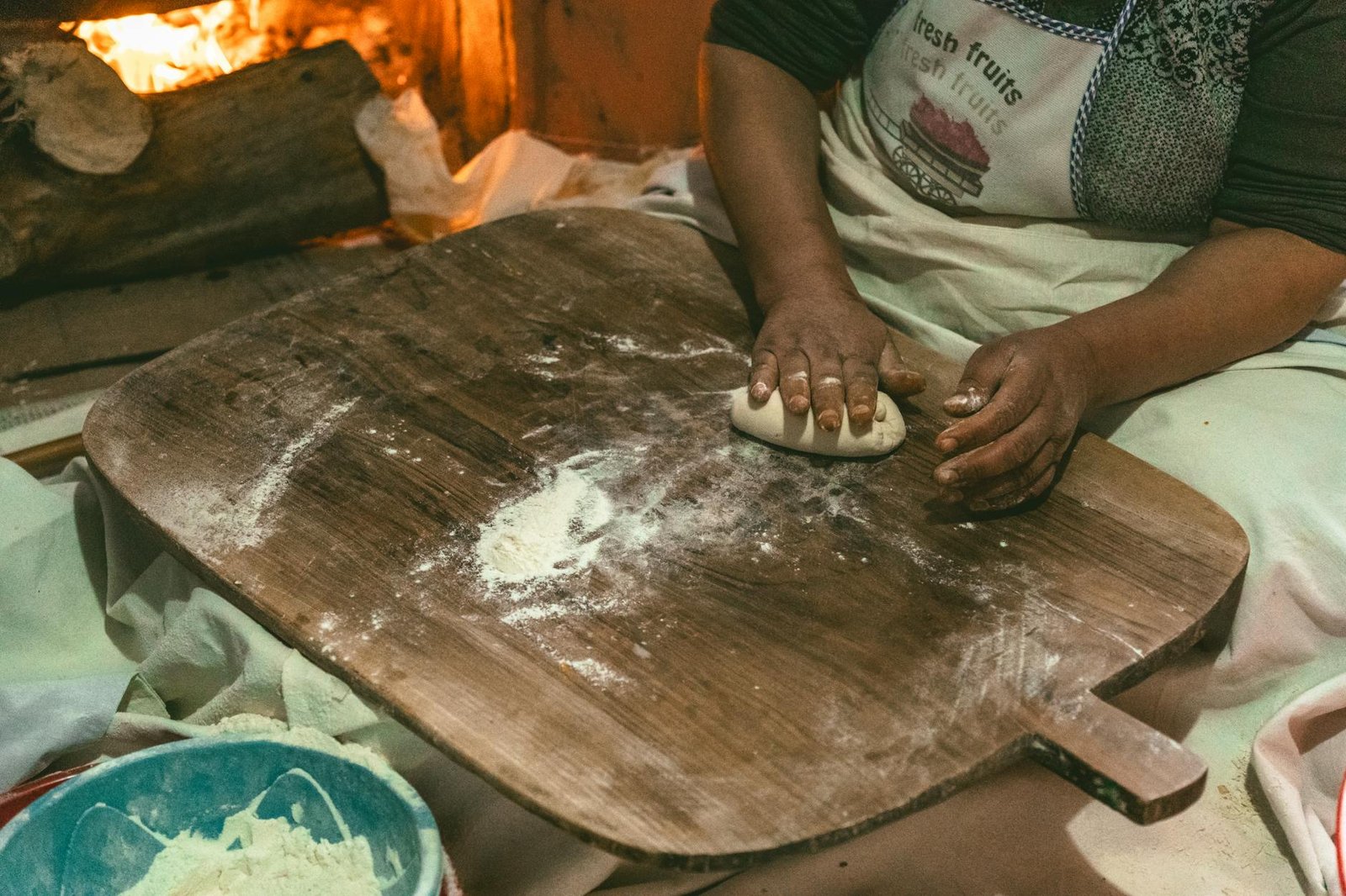 Gas Stove Repair vs Replace: A Cost Comparison and Decision Guide 2 Woman kneading dough by a fireplace in Türkiye, capturing warmth and tradition.