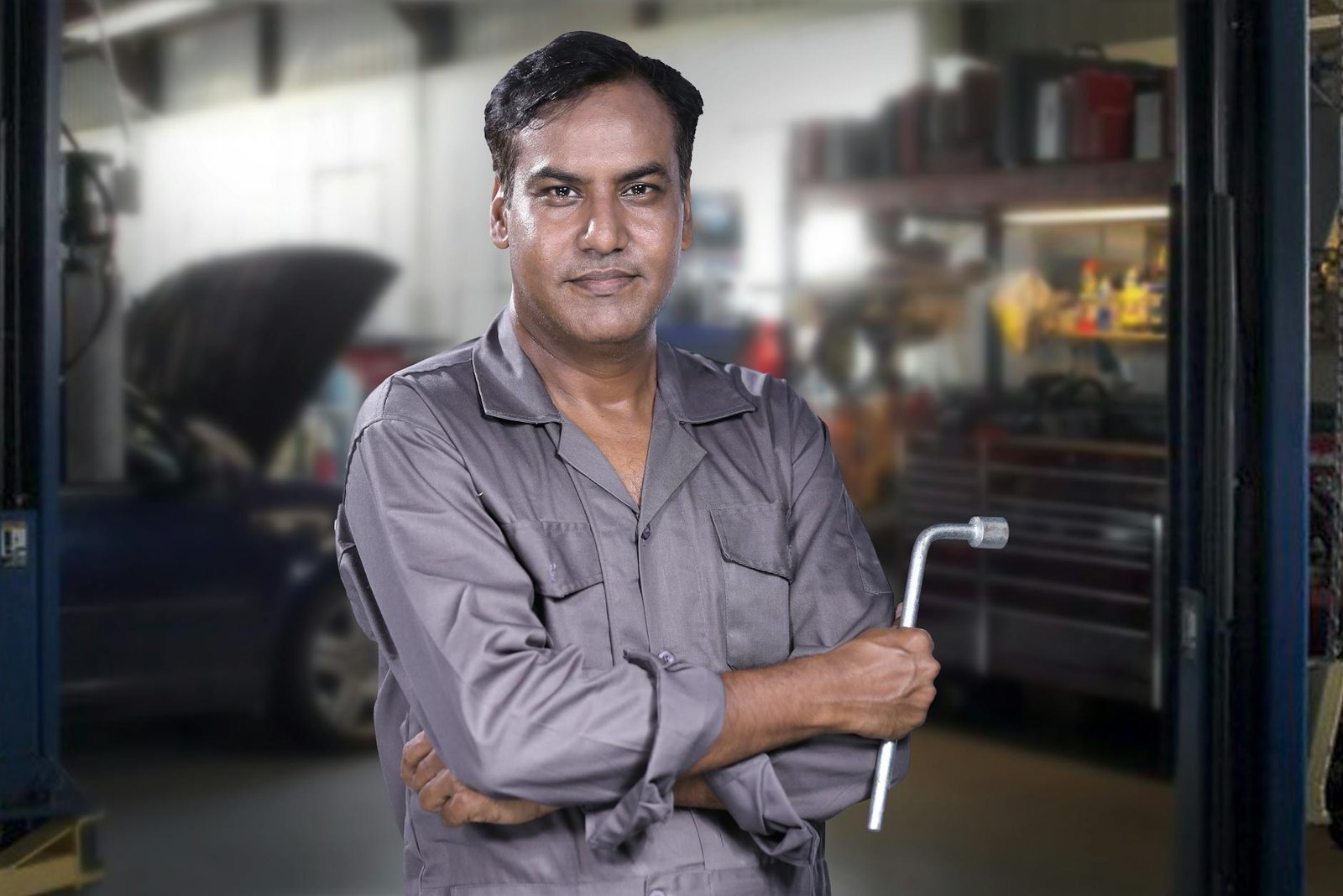 Portrait of a skilled mechanic holding a lug wrench in a Karachi auto repair shop.