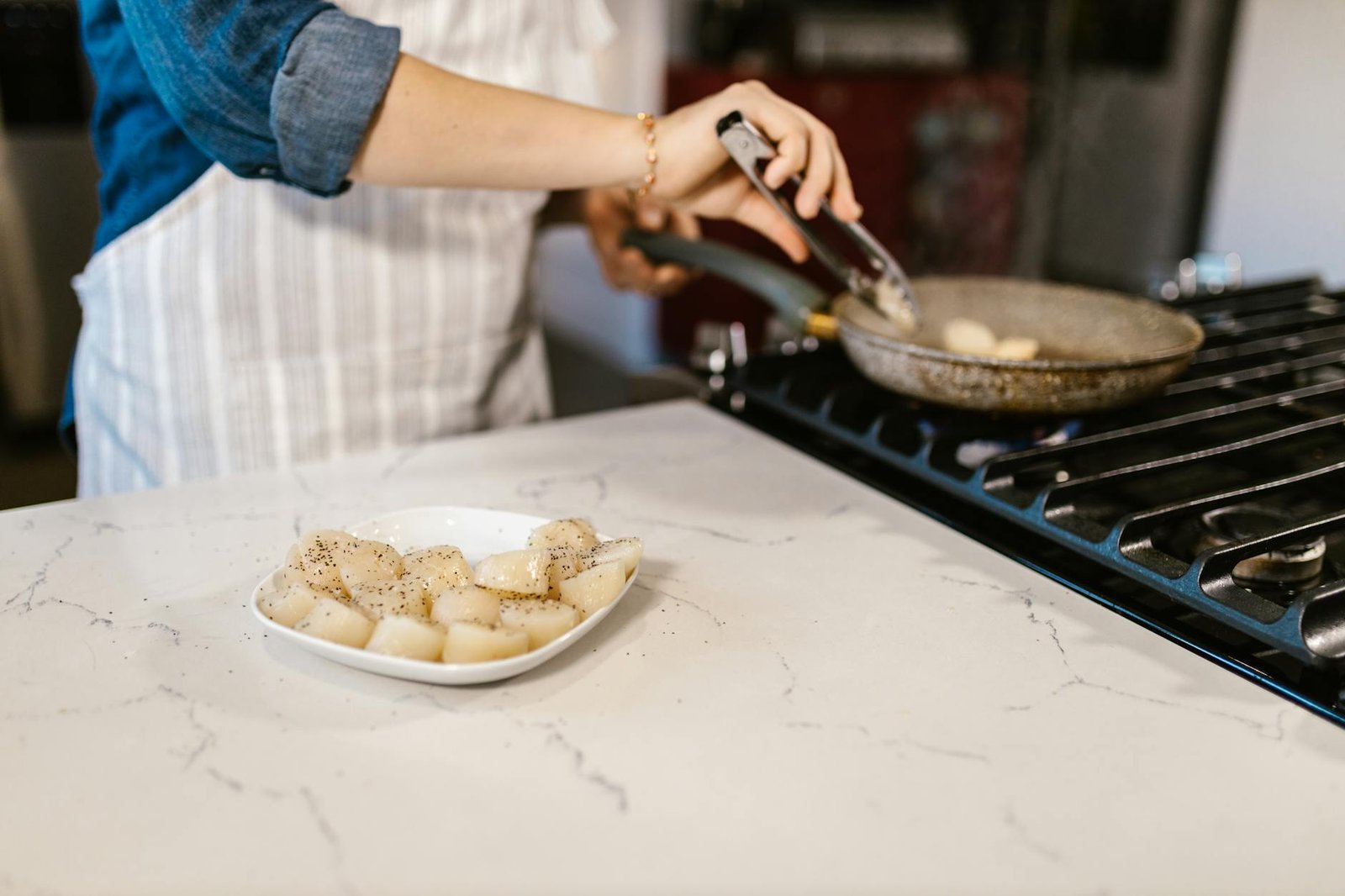 Optimizing Your Gas Stove for Energy Efficiency and Safety 2 A person cooking spiced scallops in a kitchen with a pan on a gas stove.