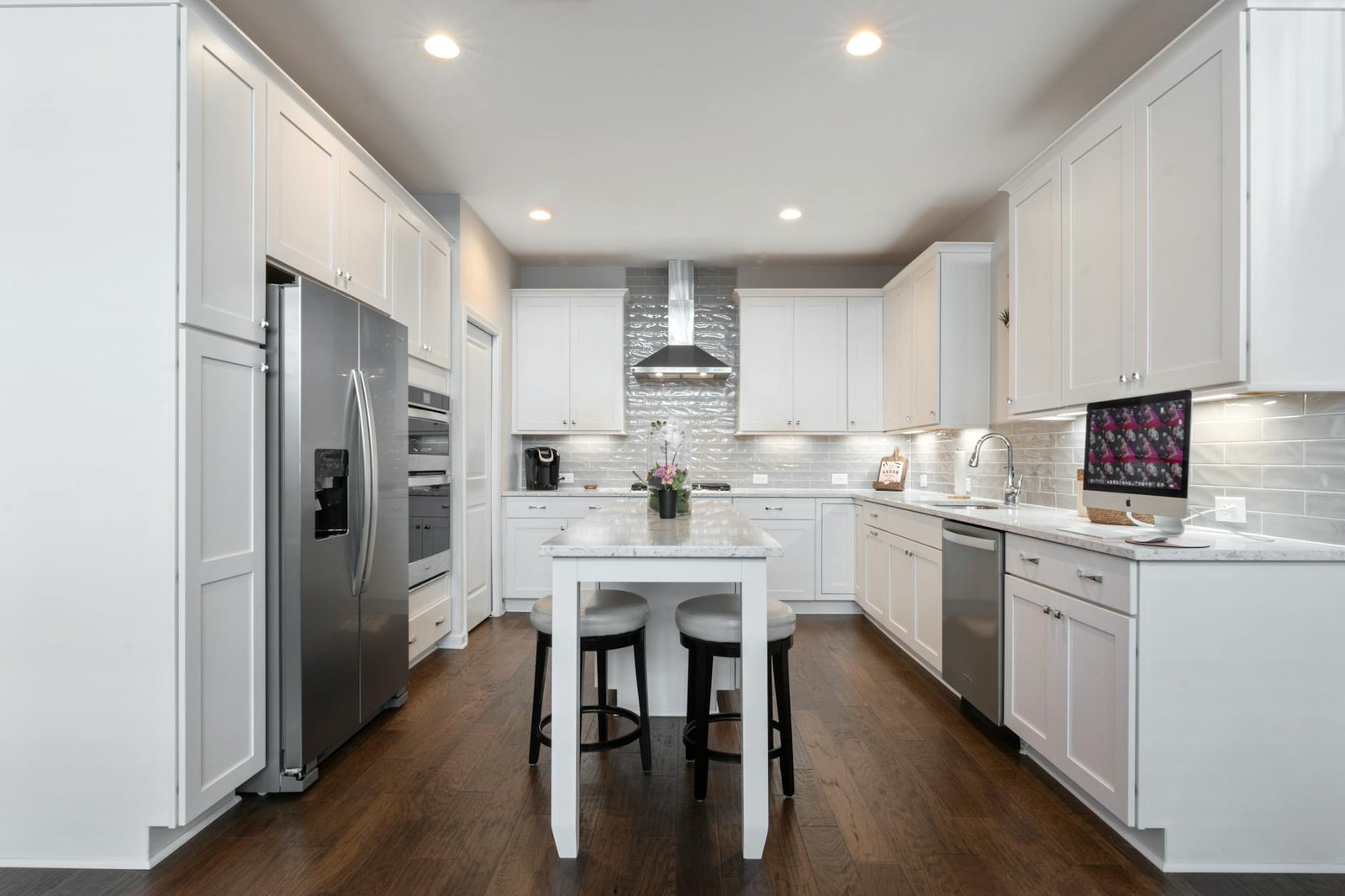 Spacious modern kitchen featuring white cabinets, island, and stainless steel appliances.