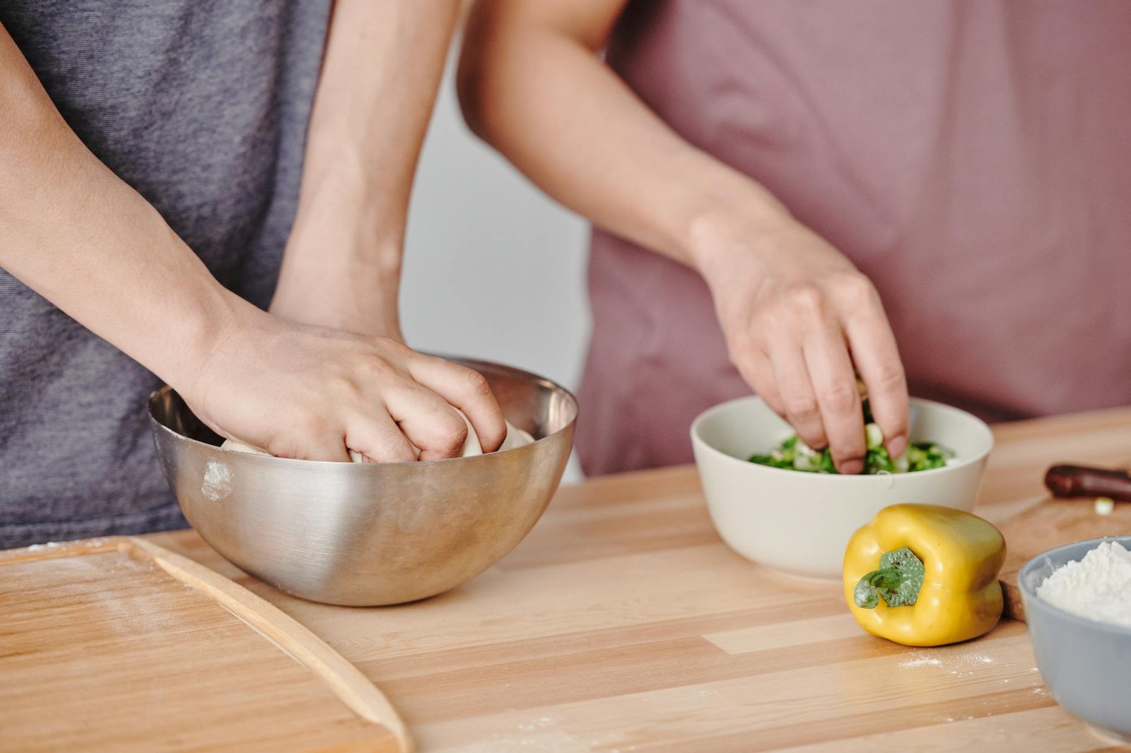 Portable Induction Cooktops for Apartment Dwellers: A Guide to Efficient Stir Frying 3 Two people preparing food by kneading dough and cutting vegetables in a kitchen setting.