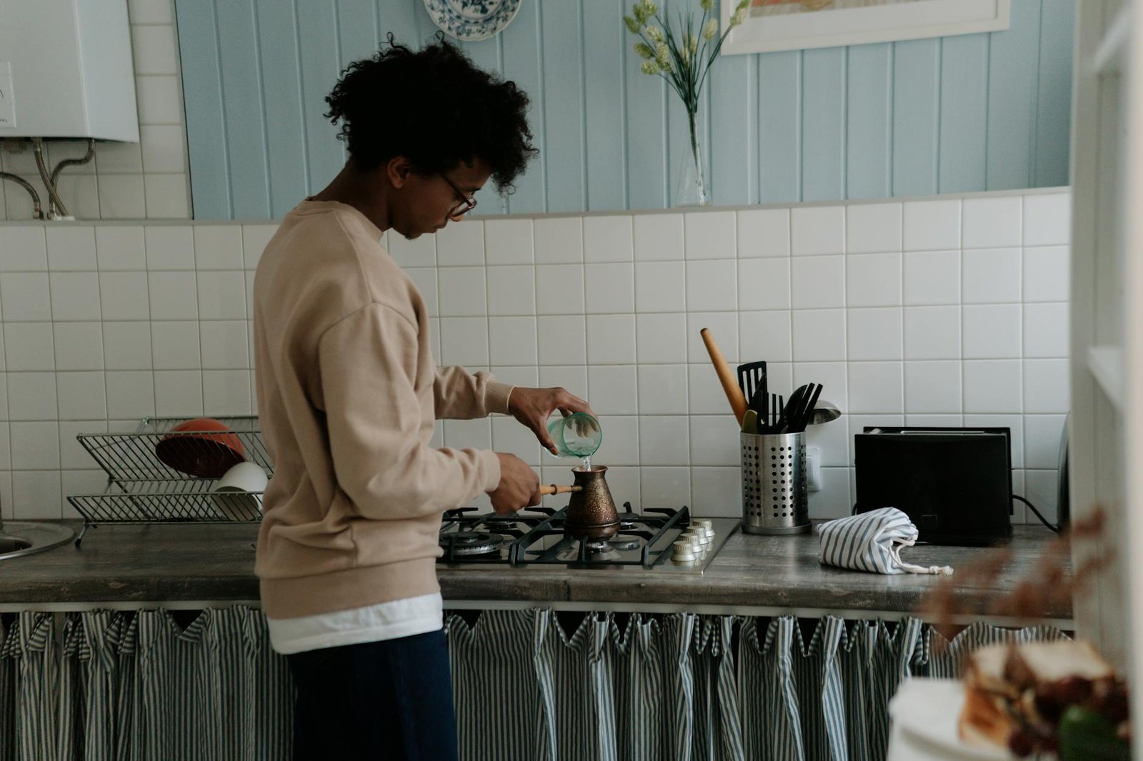 Small Stove Big Impact: Space Saving Range Top Solutions 3 A young man making coffee on a gas stove in a cozy kitchen setting.
