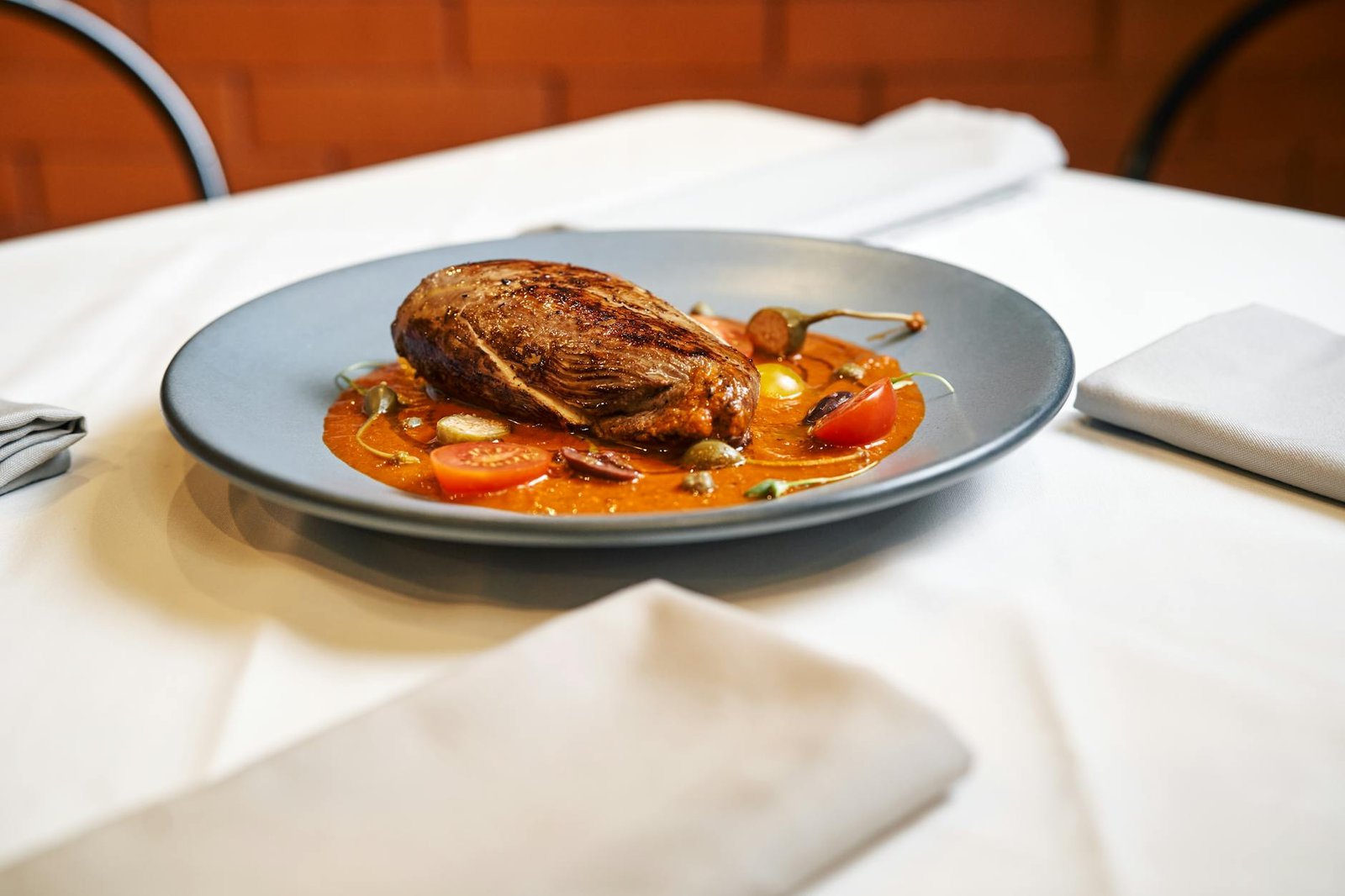 Solo Stove Pi Portable Wood Fired Oven Review for Off Grid Cooking 3 Elegant plated beef dish garnished with tomatoes on a sophisticated table setting.