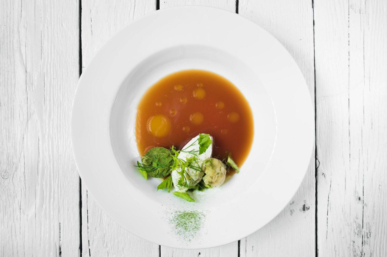 Elegant gourmet dish with rich broth and herbs on rustic wood background, ideal for culinary themes.