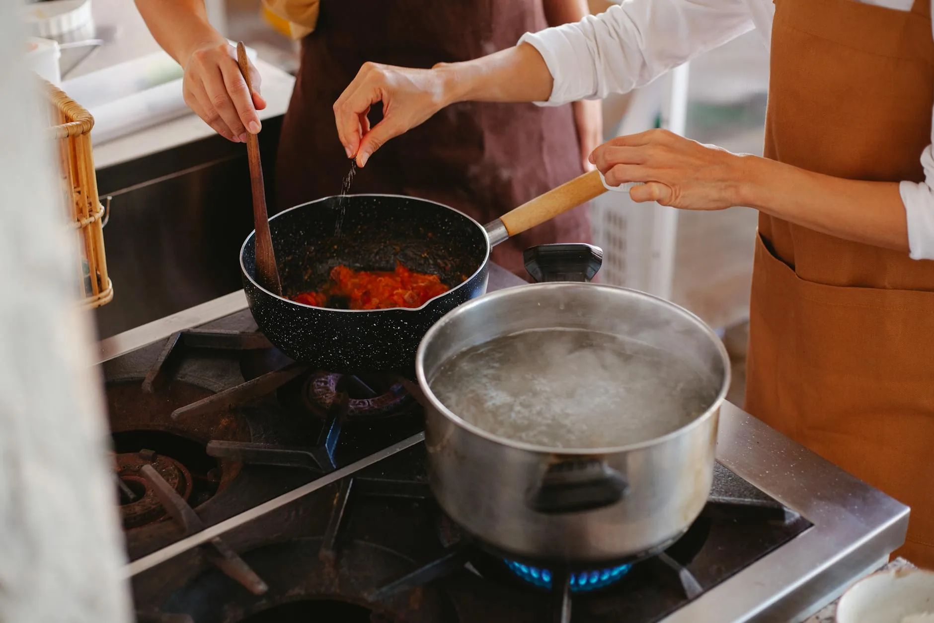 Stirring a saucepan on an electric stove — heavy-bottomed cookware buffers thermal lag and prevents simmer overshoot