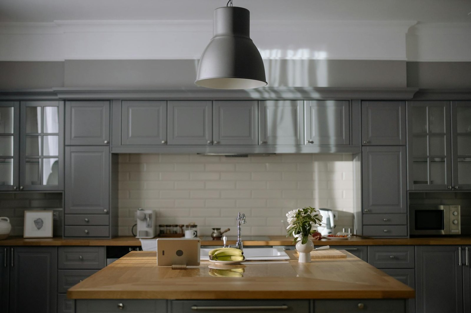 A sleek kitchen with gray cabinets, wooden countertops, and modern lighting.