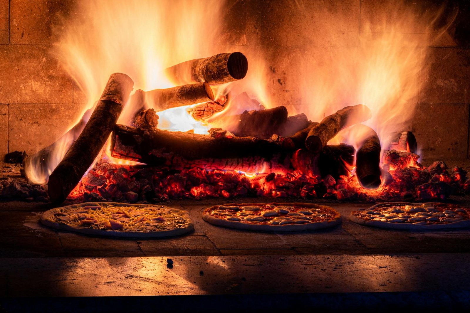 Rustic wood-fired pizza oven with flames and pizzas baking, capturing the warmth of traditional cooking.