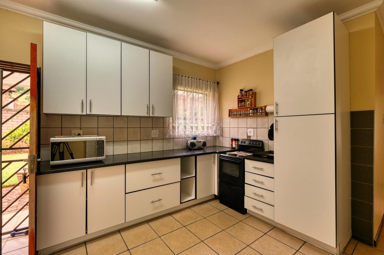 Spacious kitchen featuring white cabinets, microwave, and a stove in a Pretoria home.