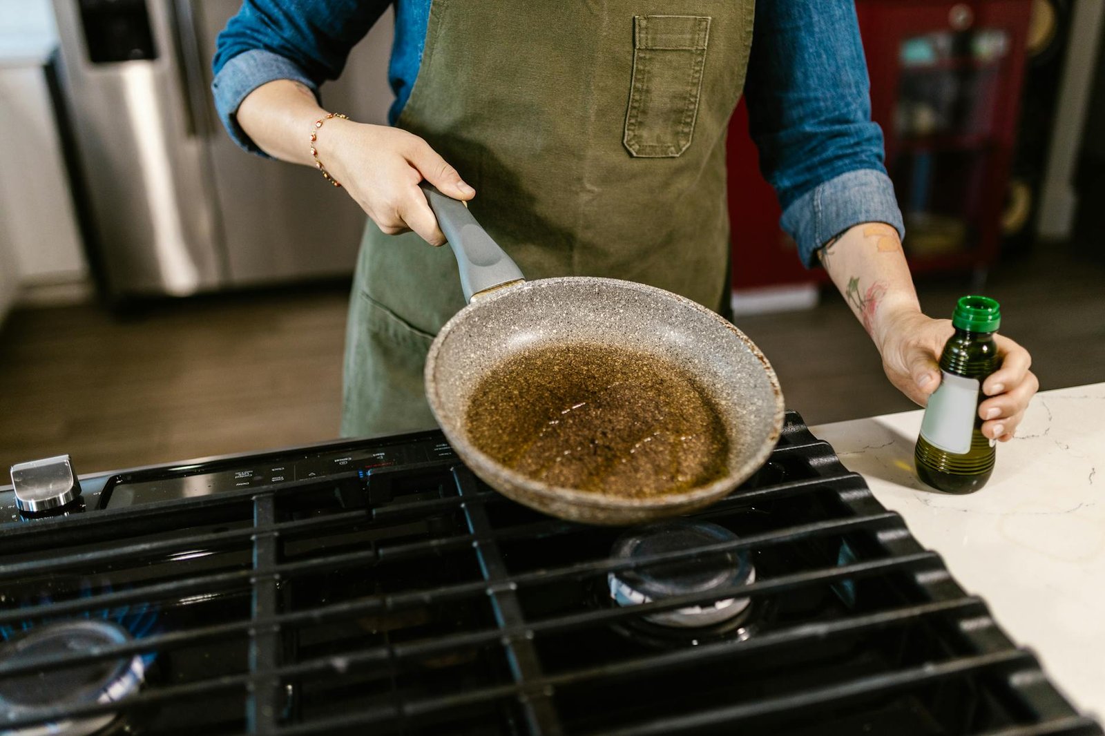 Chef holding frying pan with olive oil in kitchen, ready to cook a delicious meal.