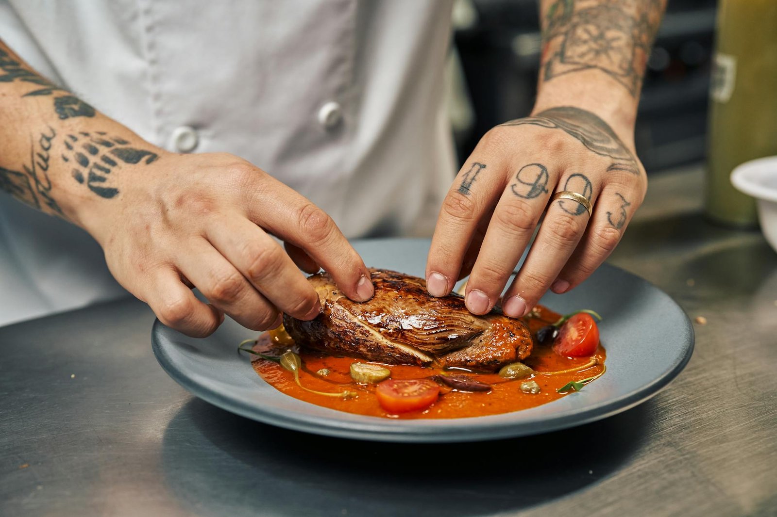 Wolf IT364C 36 Inch Induction Cooktop Review for Small Apartment Kitchens 3 Chef with tattoos presenting a perfectly cooked steak with garnishes on a colorful plate.